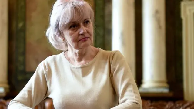 Iryna Farion the ex-Ukrainian MP - poses for an official press photograph. She's wearing a cream coloured long sleeve top and is looking towards the right of the frame.