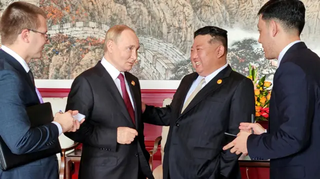 Czterech mężczyzn, dwóch Rosjan i dwóch Koreańczyków z Północy, rozmawia i śmieje się.