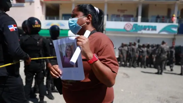 Obinrin yii mu fọto ẹbi rẹ ti ko ri mọ lẹyin iṣẹlẹ naa lọ silee faaji naa.