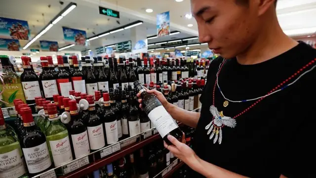 વાઇનની બોટલ જોતી એક મહિલા