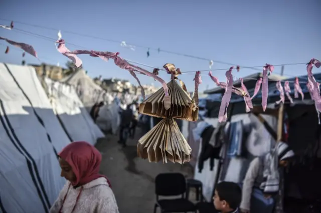 عائلة تصنع زخارف ملونة وتزين الخيام المؤقتة لإدخال البهجة على الأطفال خلال احتفالات رمضان على الرغم من الهجمات الإسرائيلية المستمرة في رفح