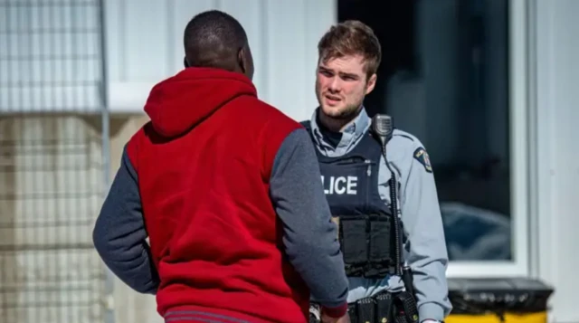 ਇੱਕ ਪੁਲਿਸ ਵਾਲੇ ਨਾਲ ਗੱਲ ਕਰਦਾ ਇੱਕ ਸਿਆਹਫਾਮ ਵਿਅਕਤੀ