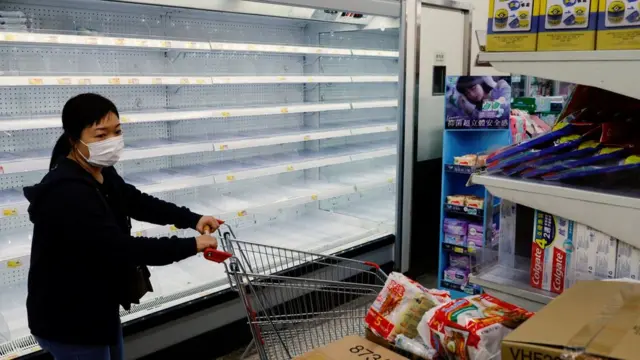 A customer wearing a face mask shops in front of partially empty shelves at a supermarket, ahead of mass coronavirus disease (COVID-19) testing, in Hong Kong, China March 4, 2022.