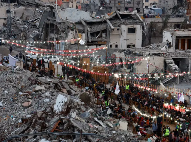 فلسطينيون يفطرون بتناول وجبات الإفطار خلال شهر رمضان المبارك، بالقرب من أنقاض المباني، وسط وقف إطلاق النار بين إسرائيل وحماس، في رفح، جنوب قطاع غزة