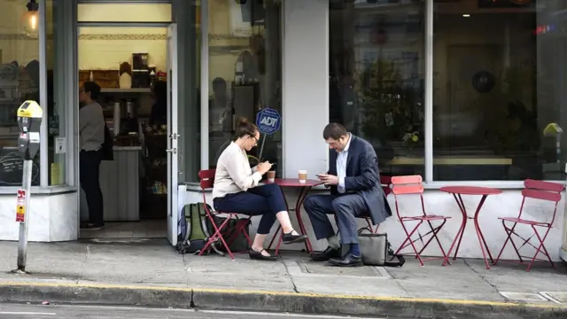 Duas pessoas tomam cafépalpites coritiba x cearamesa colocada na calçada