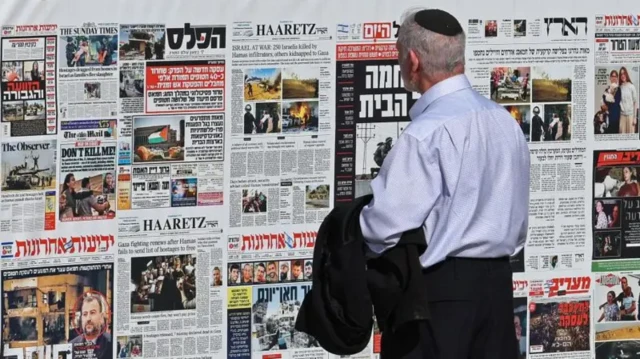 یک اسرائیلی در حال نگاه کردن به روزنامه‌هایی که به دیوار نصب شده‌اند