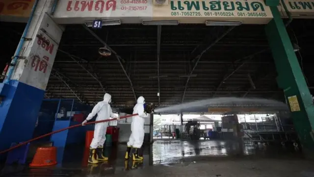 เจ้าหน้าที่ดับเพลงช่วยกันฉีดยาฆ่าเชื้อในพื้นที่ตลาดค้าส่งกุ้งแห่งหนึ่งในจังหวัดสมุทรสาคร หลังพบแม่ค้าติดเชื้อในประเทศ