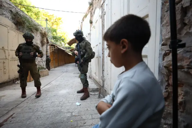 مستوطنون إسرائيليون في البلدة القديمة بمدينة الخليل جنوبي الضفة الغربية، بينما أغلقت القوات الإسرائيلية مداخل ومخارج في المنطقة بحواجز حديدية وقيّدت حركة الفلسطينيين.