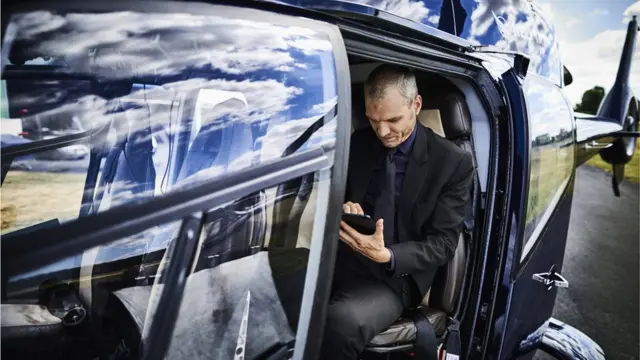 Un homme regarde sa tablette à l'intérieur d'un hélicoptère