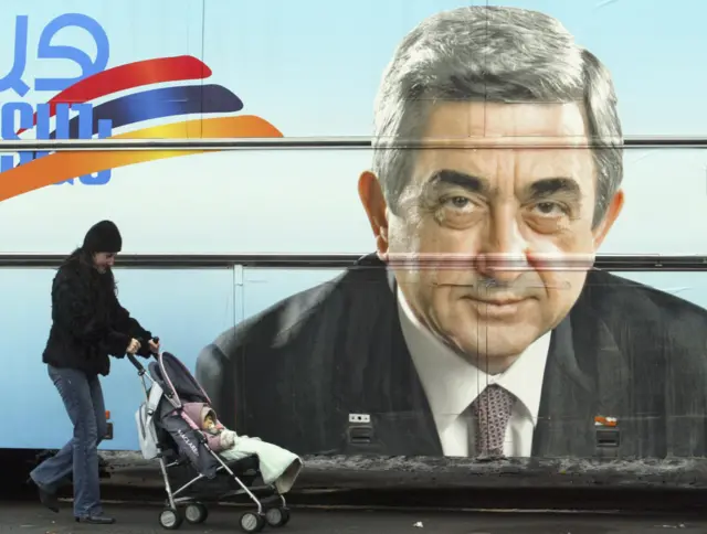 Женщина с коляской на фоне предвыборного плаката