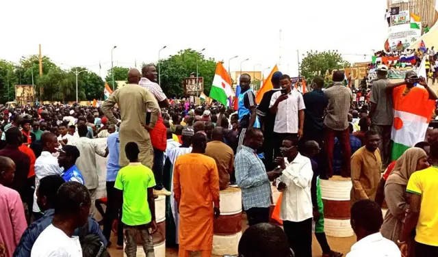 Des partisans du coup d'État agitent des drapeaux lors de la manifestation contre une éventuelle intervention militaire de la Communauté économique des États de l'Afrique de l'Ouest (CEDEAO) et des sanctions à Niamey, au Niger, le 20 août 2023.