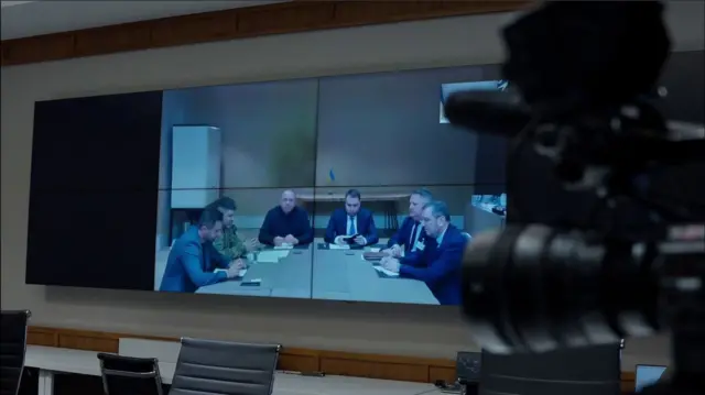 Шість членів українського переговорної делегації сидять за столом