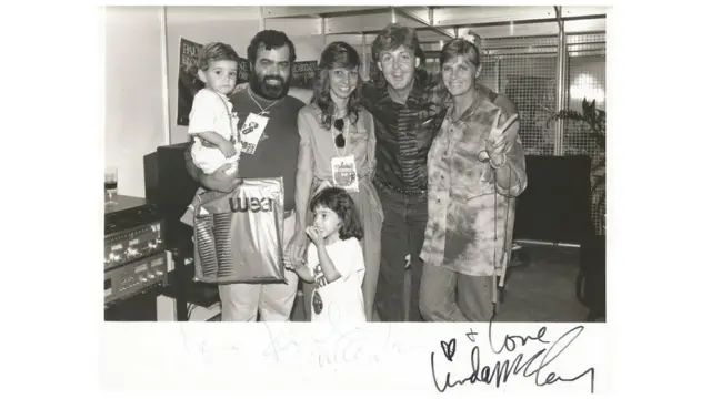 Marco Antônio Mallagoli, família e crianças posam ao lado de Paul dentro de camarim, todos sorrindo