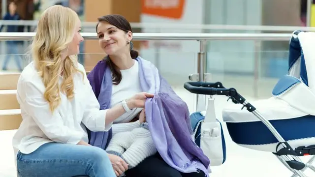 Ibu menyusui anaknya di sebuah pusat keramaian.