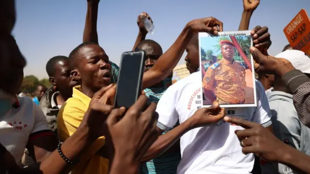 Des manifestants réunis à Ouagadougou pour soutenir les militaires tiennent une photo du lieutenant-colonel Paul-Henri Sandaogo Damiba, chef de la mutinerie et du Mouvement patriotique pour la protection et la restauration (MPSR), le 25 octobre 2022.