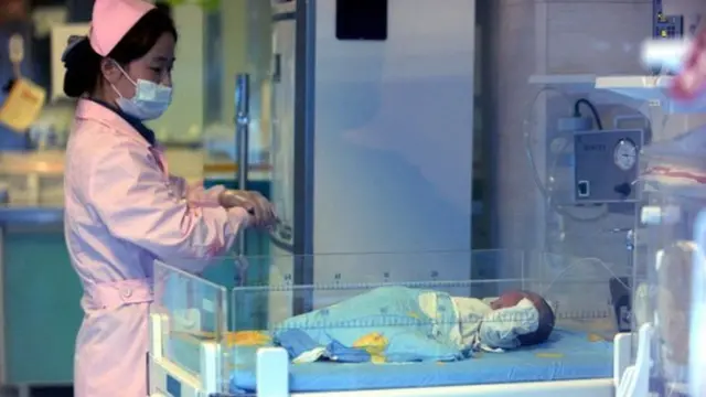 একজন নার্স শিশুর দিকে তাকিয়ে