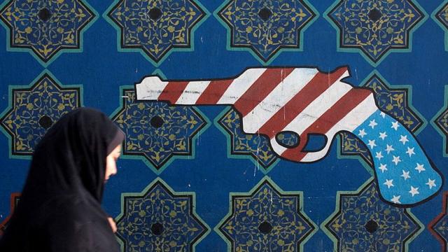 Женщина проходит мимо граффити в Тегеране