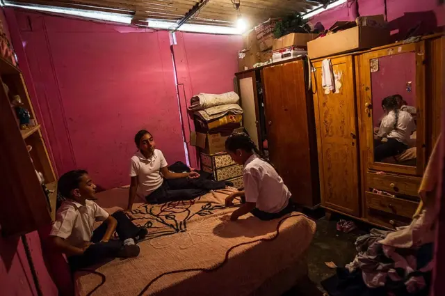 Three sisters sit on their bed