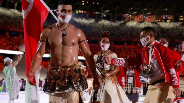 ঐতিহ্যবাহী জাতীয় পোশাক পরে টোংগার পতাকা বহন করছেন টোওফাটোফা।