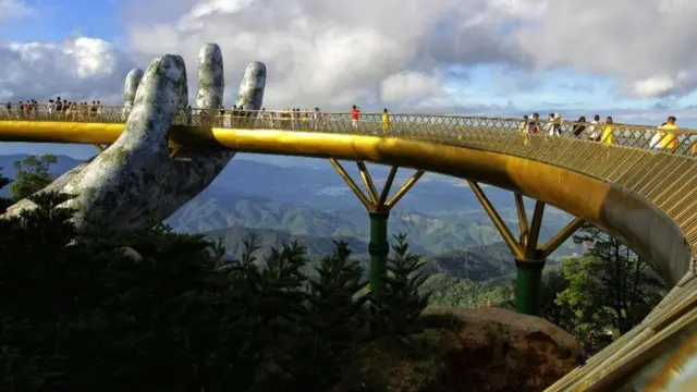 In this photograph taken on July 31, 2018, visitors walk along the 150-meter long Cau Vang "Golden Bridge" in the Ba Na Hills near Da Nang.