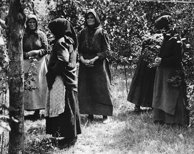 Mulheres com as cabeças cobertas por capuz em um gramado