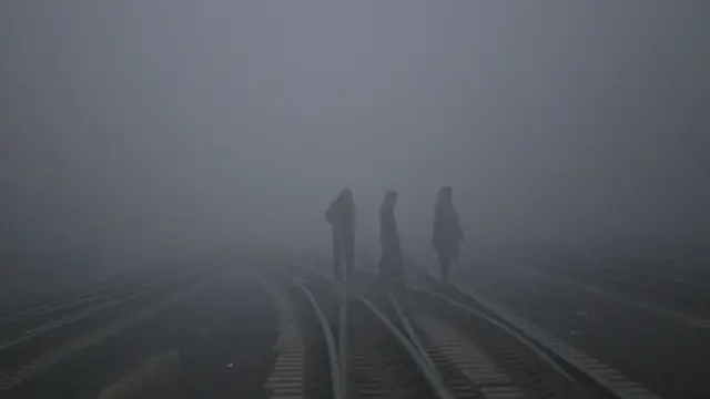 রেইললাইনের ওপর দিয়ে কুয়াশার মাঝে হাঁটছেন তিনজন 