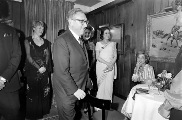 ১৯৭৫ সালে নিউ ইয়র্কে হেনরি কিসিঞ্জার (মাঝে), নুসরাত ভুট্টোর (ডান থেকে দ্বিতীয়) সাথে আশরাফ পাহলাভি