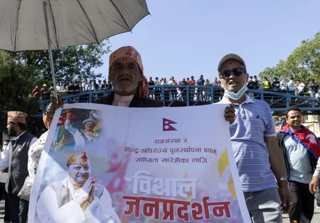 राजावादीहरूको प्रदर्शनका सहभागी ब्यानर बोक्दै 