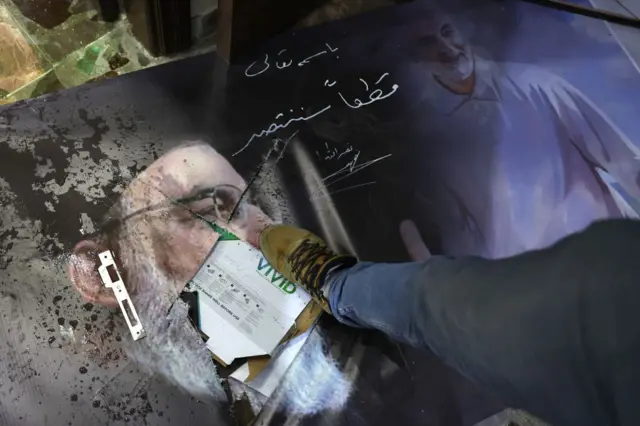 Bir adam Hasan Nasrallah'ın resmine basıyor. 