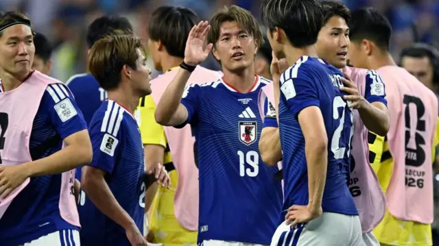 青色ユニホームの日本代表選手らとピンクのビブを着けた選手らが密集している