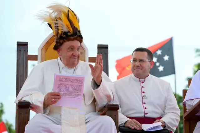 Papa Francisco com cocar ao lado de missionário da Pro-Catedral da Santa cruz, na Papua-Nova Guiné