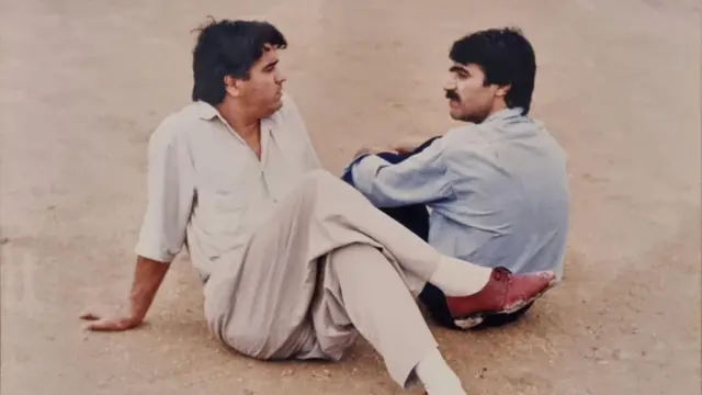دو مرد روبه‌روی هم روی زمین نشسته‌اند 
