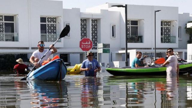 Des habitants déplacent leurs affaires sur des kayaks dans un quartier résidentiel inondé à Dubaï en avril 2024.