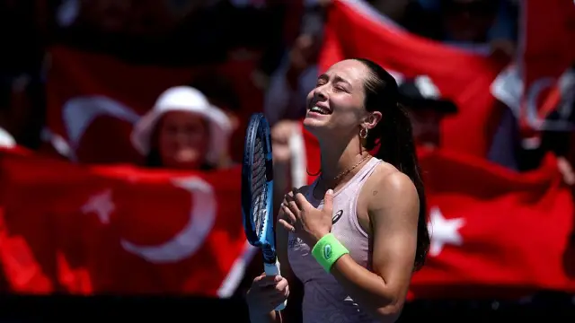 Sönmez maç sonunda sevinirken arkasında fonda çok sayıda Türk bayrağı görülüyor. Sönmez elini kalbine koymuş, diğer elinde raketi var.