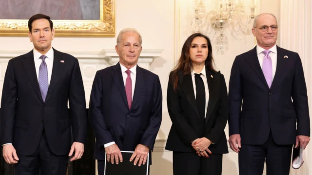 Biri kadın dört resmi giysili yetkili gazetecilere poz veriyor. 