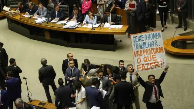 Deputado ergue cartaz com os dizeres "deixe o homem trabalhar"