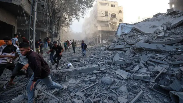 غزيون يهرعون للاحتماء بعد غارة إسرائيلية استهدفت مبنىً في مخيم البريج للاجئين الفلسطينيين وسط قطاع غزة في 19 أكتوبر/تشرين الأول 2025