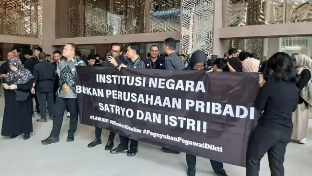 Salah satu spanduk demo ASN Kemendikti Saintek bertuliskan: "Institusi negara bukan perusahaan pribadi Satryo dan istri."
