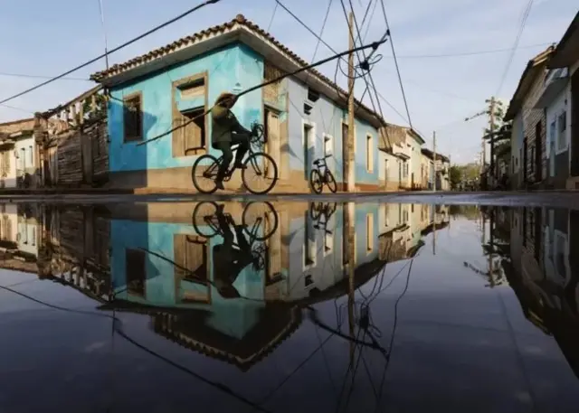 Un homme conduisant un vélo dans une zone inondée