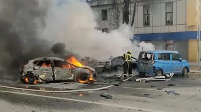 Bombeiro tenta apagar carro em chamas após um ataque de forças ucranianas à cidade de Belgorod, segundo informações de autoridades russas