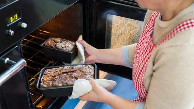 Жінка витягує хліб з печі - стокова фотографія