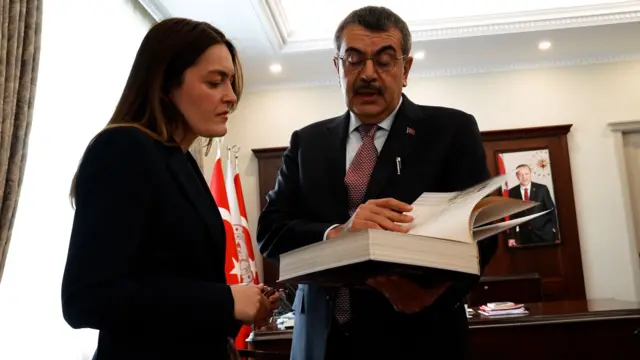 Yusuf Tekin, BBC Türkçe Muhabiri Fundanur Öztürk'e gazeteciye elinde tuttuğu bir kitaptan örnekler gösteriyor.