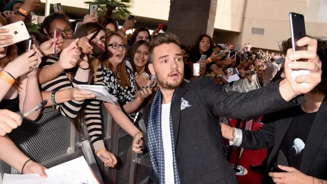 Liam Payne takes a selfie with a large group of fans outside an awards ceremony in 2015