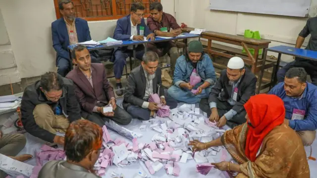 床に敷いた白い敷物の上で投票用紙を数える職員たち