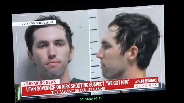 Фотография Тайлера Робинсона, подозреваемого в убийстве Чарли Кирка на мониторе телевизора, такст в подписи цитирует фразу губернатора Юты "Мы взяли его" и фразу "Привет фашист" выгравированную на гильзе от пули стрелявшего