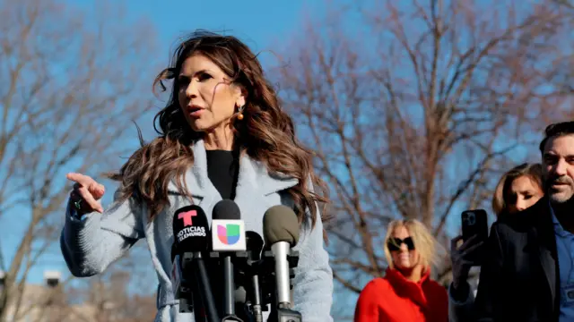 Kristi Noem señala con su índice de derecho mientras habla ante los periodistas en un espacio exterior en Washington DC.
