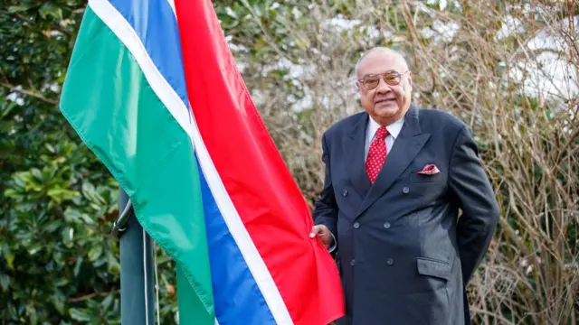 Gambian high commissioner, Francis Blain pose with dia flag during di welcome back ceremony for Commonwealth headquarters London.