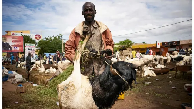 رجل يقف وسط سوق للغنم والماعز