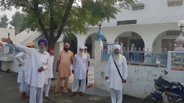 भारतीय पंजाब के एक गांव के गुरुद्वारे में जमा लोग.