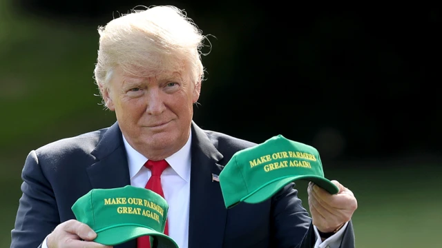 特朗普手持两顶印有“让我们的农民再次伟大”(Make Our Farmers Great Again)字样的绿色帽子